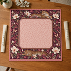 Burgundy vegan leather Mahjong mat with leopards and cream magnolias overhead on an oak table