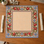 Vegan leather Mahjong mat with pomegranates and a peach checkerboard center overhead on an oak table