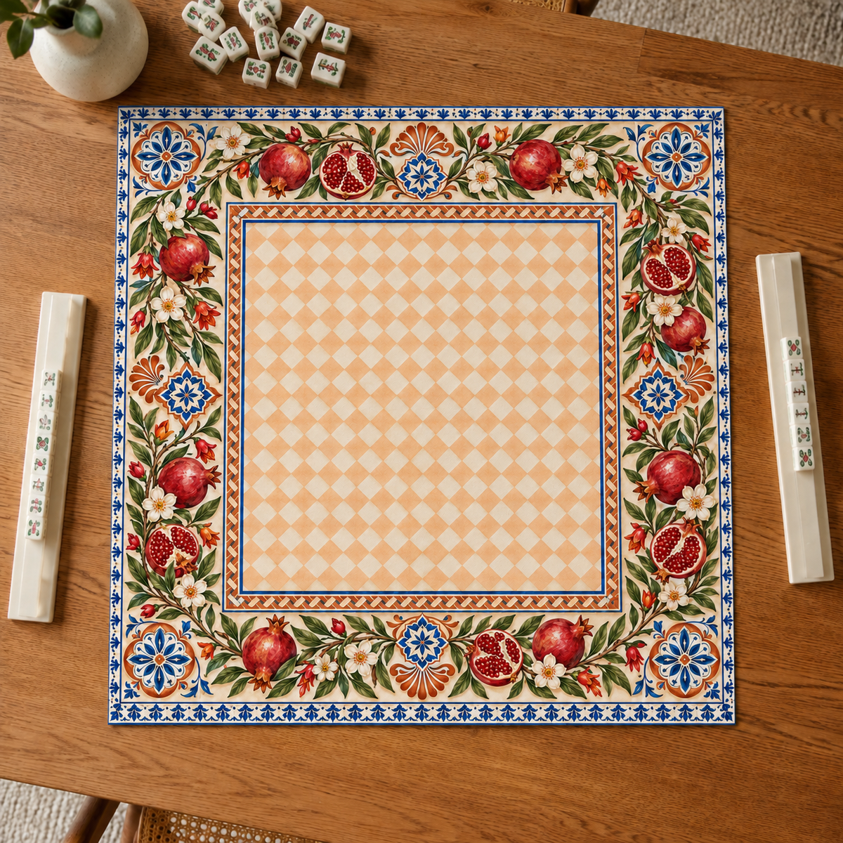 Vegan leather Mahjong mat with pomegranates and a peach checkerboard center overhead on an oak table