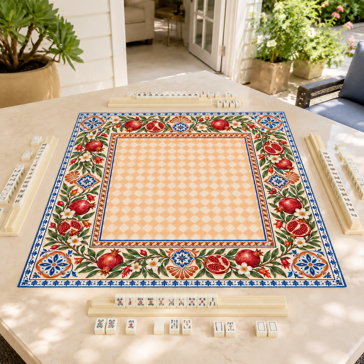 Vegan leather Mahjong mat with pomegranates and a peach checkerboard center on a sunlit patio table