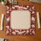 Burgundy Art Deco vegan leather Mahjong mat with white cranes and magnolias overhead on an oak table