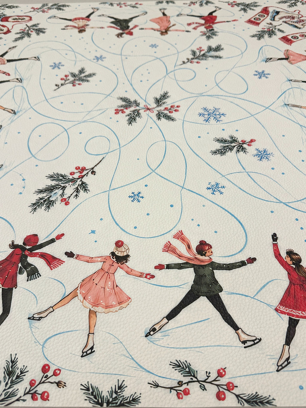 Close-up of ice skaters in pink, red and dark green outfits with blue skating trails on the cream Mahjong mat