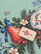 Textured vegan leather surface with a red ornament, Mahjong tile and blue ribbon on the green Merry Mahj mat