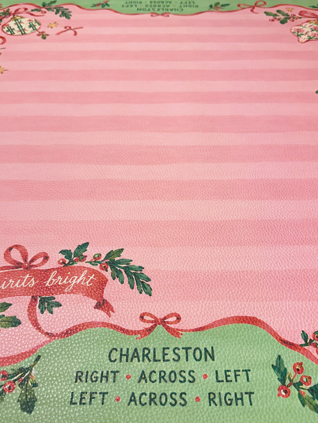 Close-up of printed Charleston passing reminders on the green border of the pink striped Christmas Mahjong mat