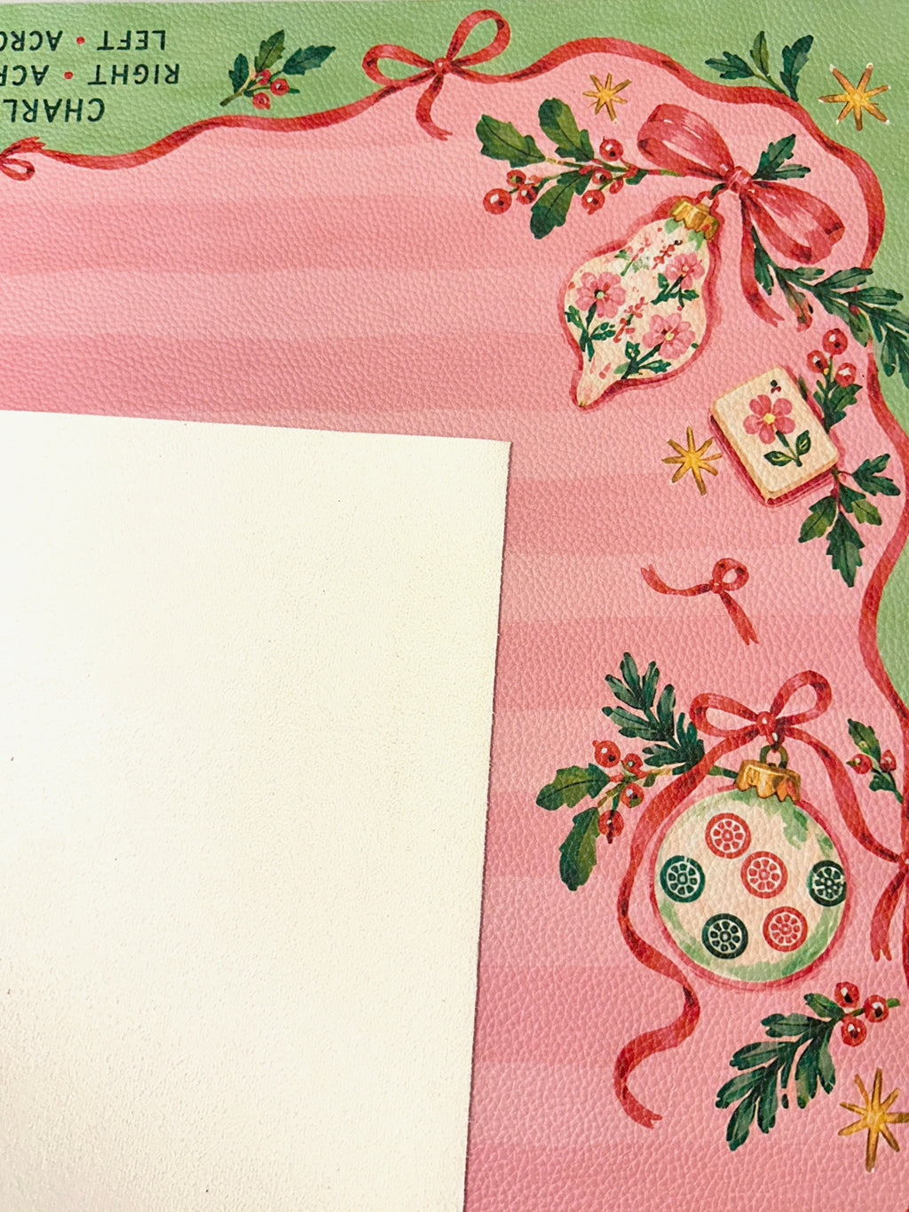 Cream suede backing beside the pink and green Christmas Mahjong mat with ornament, ribbon and Mahjong tile details