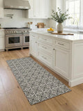 May include: A rectangular kitchen rug with a black and white floral pattern. The rug is placed on a hardwood floor in front of a white kitchen island. The kitchen has white cabinets and stainless steel appliances.