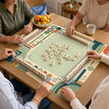Jade green lines, terracotta circles and cream geometric blocks border the light green center of this mid-century Mahjong mat.