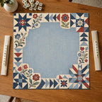 Printed patchwork stars, geometric blocks and folk flowers frame a dusty blue center on an Americana Mahjong mat.