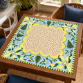 Christmas Mahjong mat with cream patterned center, pale blue border, yellow striped bows and Christmas trees on a wooden game table