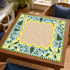 Christmas Mahjong mat with cream patterned center, pale blue border, yellow striped bows and Christmas trees on a wooden game table