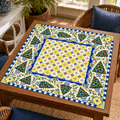 Christmas Mahjong mat with blue-and-yellow tile-style center, Christmas trees, leafy branches and floral corners on a wooden game table