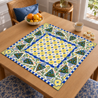 Angled table view of the Christmas Mahjong mat with blue-and-yellow tile-style center, Christmas trees, leafy branches and floral corners